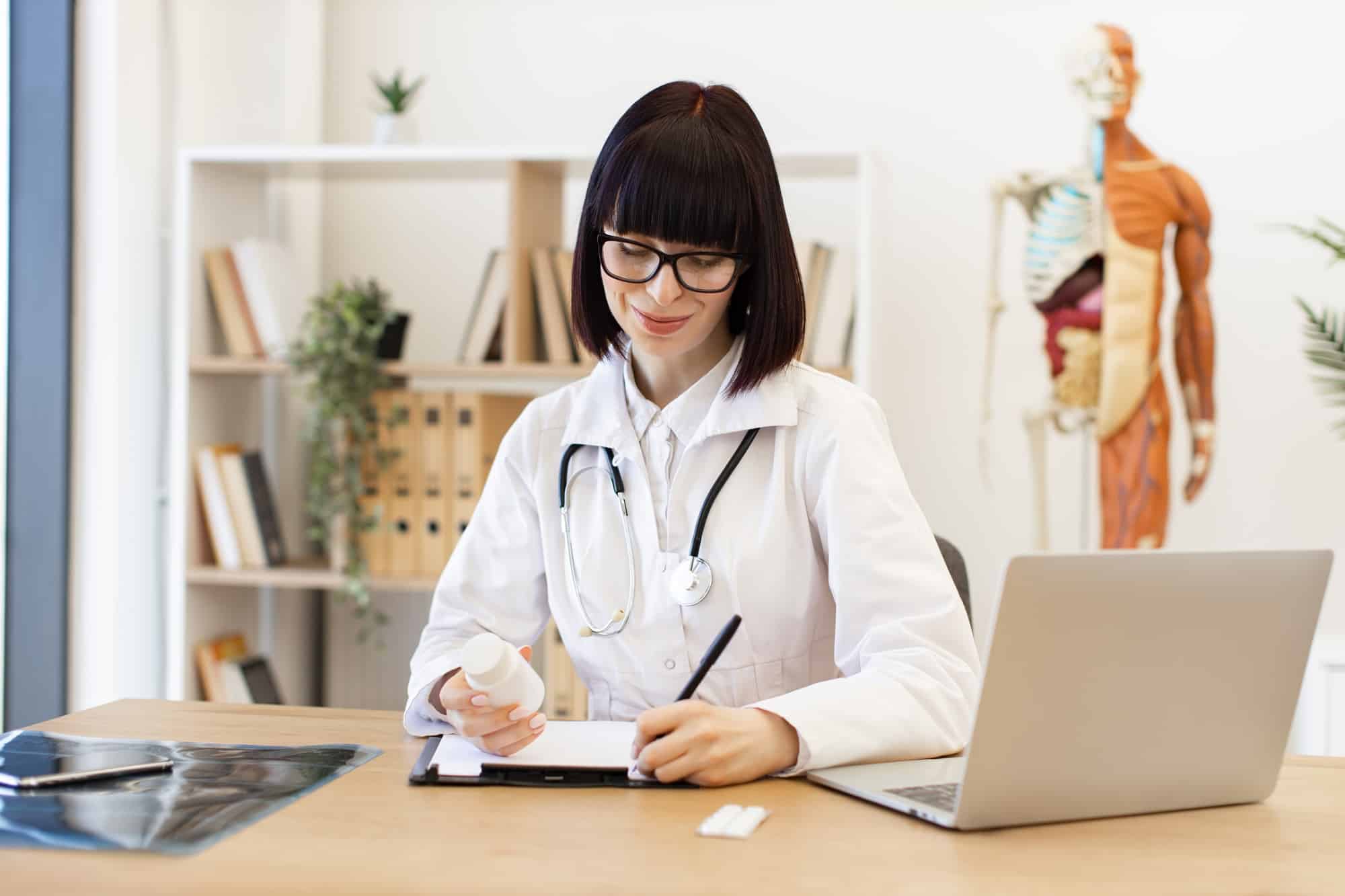 Female doctor writing prescription in medical office